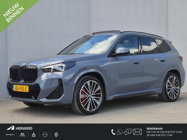 BMW X1 xDrive30e 326 PK M-SPORT / Fabrieksgarantie tot 03-2028 / Glazen schuif- en kanteldak / Head Up Display / Elektrisch trekhaak / Trekgewicht 1800 kg / Harman Kardon Audio Systeem / Elektrische achterklep / Rondomzicht camera / Stuur- & Stoel verwarming / A