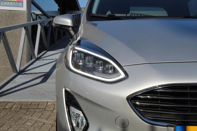 Ford FIESTA 1.0 EcoBoost Titanium Navigatie/Adaptive cruise control/Climate control/Lane assist/Apple carplay/Stoelverwarming/Stuurverwarming/Voorruitverwarming/Achteruitrijcamera/Parkeersensoren rondom/Dodehoek detectie/Keyless/Bluetooth/Lichtmetalen velgen.